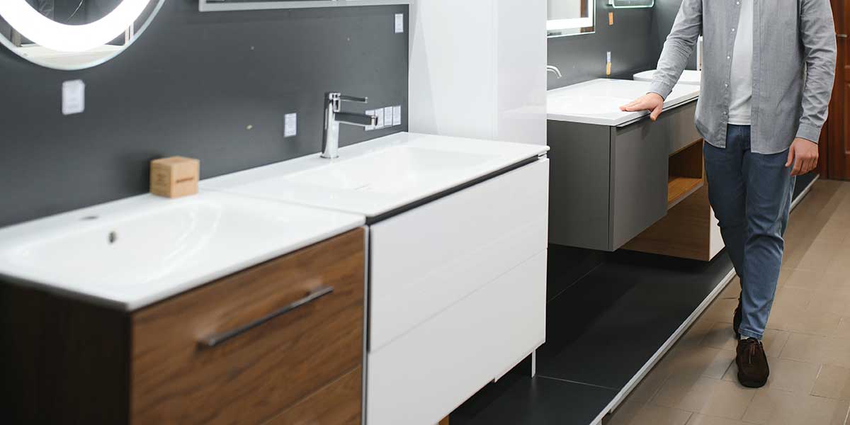 Bathroom cabinet material selection A man examines modern vanities in a showroom, highlighting options for choosing the right material for your bathroom cabinets.