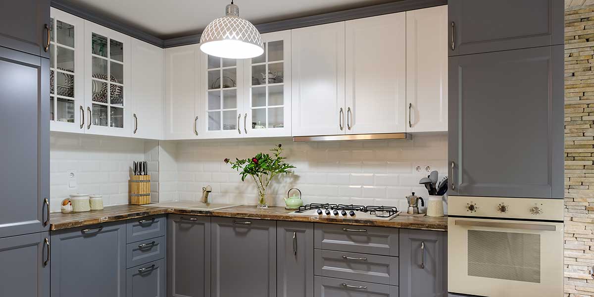 Two-Tone Kitchen Cabinet Guide Modern kitchen featuring white upper cabinets and dark grey lower cabinets, paired with a white tile backsplash and wooden countertops.